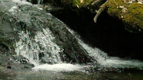 Slow-motion-shot-of-small-waterfall-spilling-into-a-mountain-pool-shot-at-180-frames-per-second