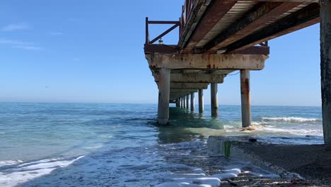 filmed-under-a-pier-in-teh-south-coast-of-spain,-spanish-sea-vacation-time-lapse-of-sea-moving-under-pier