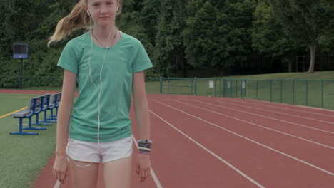 Teen-girl-walks-on-a-high-school-track-smiling-to-herself-in-slow-motion
