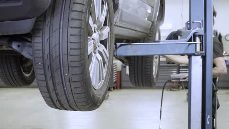 Car-mechanic-checking-tire-pressure-on-the-car-on-the-lift-at-high-quality-car-workshop