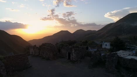 Aerial-drone-shot-of-ruins-at-sunset-in-the-ghost-town-Real-de-Catorce-and-mountains,-San-Luis-Potosi-Mexico