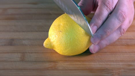 Schneiden-Sie-Eine-Frische-Zitrone-Mit-Einem-Kochmesser-Auf-Einem-Hölzernen-Schneidebrett-In-Der-Küche