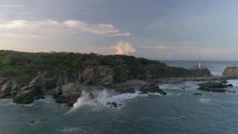 Aerial-cinematic-drone-shot-of-rock-formation-and-houses-in-Zicatela-beach-in-the-morning,-Puerto-Escondido,-Oaxaca