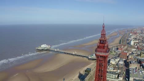 Stunning-aerial-footage,-view-of-Blackpool-Tower-by-the-award-winning-Blackpool-beach,-A-very-popular-seaside-tourist-location-in-England-,-United-Kingdom,-UK