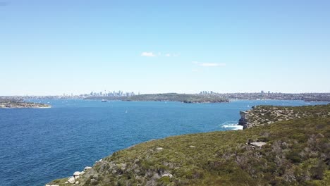 Aerial-flight-over-the-rugged-coastline-of-North-Head,-Manly