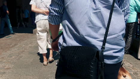 Slow-motion-girl-walking-with-her-small-french-bulldog-in-the-city,-The-woman-is-wearing-a-purse-and-is-keeping-the-dog-on-a-leash