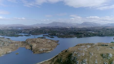 Sideways-aerial-of-a-vast-lake-with-multiple-islands-in-an-overwhelming-mountainous-Scottish-region