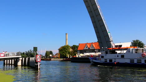 Tour-boat-fith-tourist-crossing-under-Drawbridge,-Motlawa-river,-Gdansk,-Poland
