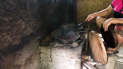 Medium-shot-of-an-Asian-woman-roasting-coffee-in-a-rural-hut-in-Bali,-Indonesia