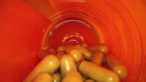 pulling-out-of-the-entire-length-of-a-orange-supplement-pill-bottle,-revealing-bottle's-cap