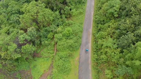 Aerial-shot-of-an-Indian-male-riding-through-the-mountains-route-in-a-remote-village,-Tamei,-Manipur,-India