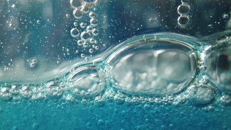 Burbujas-Grandes-Y-Pequeñas-Caen-Lentamente-En-Líquido-Azul,-Fondo-Fluido