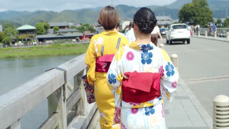 Beautiful-girl-wearing-a-traditional-kimono-looking-at-the-veiw-walking-on-a-bridge-in-Kyoto,-Japan-soft-lighting-slow-motion