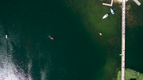 Luftaufnahme:-Draufsicht-Auf-Die-Trakai-Inselbrücke-In-Sehr-Großer-Höhe-Mit-Grünem-See-Und-Herumfahrenden-Booten
