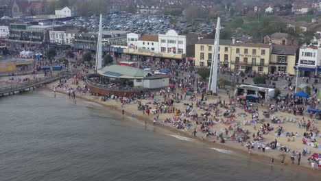 Very-busy-beach-Southend-shakedown,-seafront,-beach-bar-and-amusements-in-background