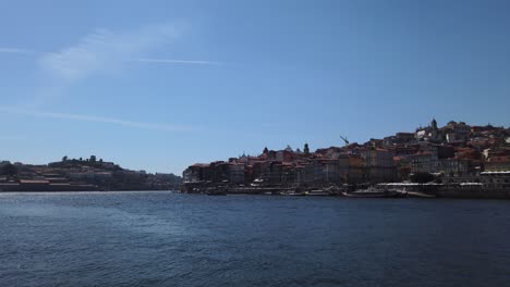 Looking-across-Douro-River-to-north-bank-near-Ribeira-on-clear-sunny-day-in-Porto,-Portugal