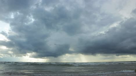 Time-lapse-of-dramatic-dark-storm-clouds-moving-fast-over-the-Baltic-sea-at-Liepaja-towards-the-camera,-low-angle-wide-shot