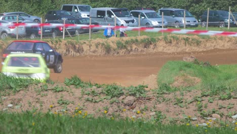 Autocross-cars-compete-in-amateur-racing-on-the-dirt-track-in-sunny-summer-day,-flat-out-cornering,-medium-shot-from-a-distance