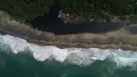 Aerial-cenital-drone-shot-of-the-beach-and-the-black-lagoon-in-the-mangrove-La-Ventanilla,-Oaxaca