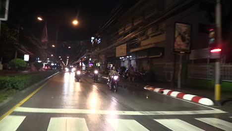 Vista-Desde-La-Parte-Trasera-De-Un-Rickshaw-En-Movimiento-En-La-Calle-Y-El-Tráfico-Que-Pasa-Por-La-Noche,-Tailandia