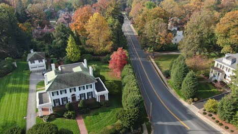Rich-neighbourhood,-aerial-view-of-luxury-mansion,-villa-in-residential-area-with-lots-of-trees-in-autumn-coloured-foliage