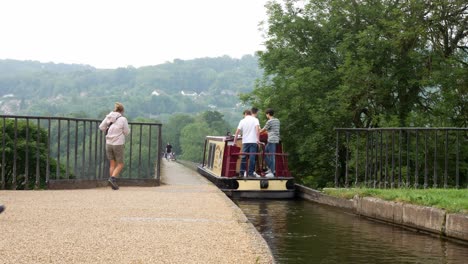 British-tourist-steering-canal-boats-onto-historic-Pontcysyllte-Aqueduct-Welsh-countryside-waterway