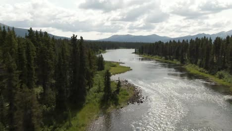 Aerial-footage-flying-up-a-river-through-the-trees-to-reveal-two-fly-fisherman-fishing-on-the-river