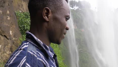 Close-up-shot-of-an-African-mans-face-as-he-stands-behind-a-pouring-waterfall