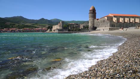 Waves-lap-onto-the-tranquil-pebble-beach-in-the-bay-of-Collioure-on-a-windy-hot-summers-day