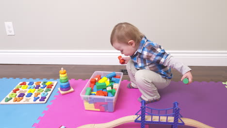 Inquisitive-toddler-boy-playing-with-his-blocks-and-other-toys
