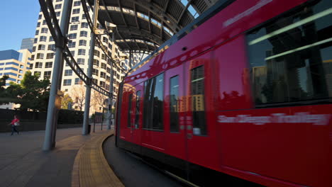 The-beautiful-red-San-Diego-Trolley-arriving-at-the-American-Plaza-station-in-downtown-San-Diego,-California
