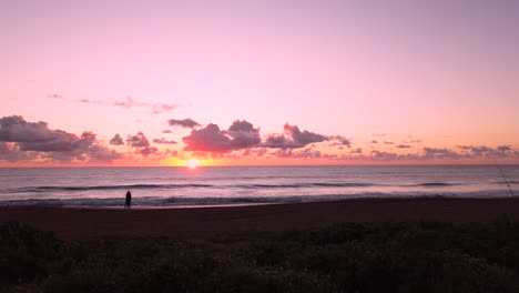 UHD-Hawaii-Kauai-static-of-couple-in-distance-on-beach-watching-partly-cloudy-sunrise