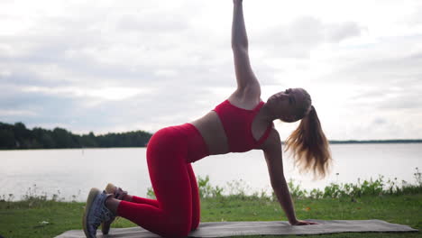Junge-Frau-In-Roter-Sportbekleidung,-Die-Draußen-Auf-Einer-Yogamatte-Sitzt-Und-Übungen-Macht-Und-Yoga-Praktiziert