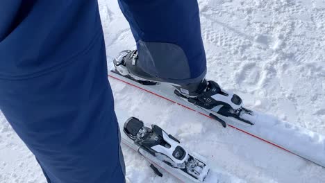 Ein-Skifahrer-Steigt-Auf-Einem-Weißen-Paar-Ski-In-Die-Bindung