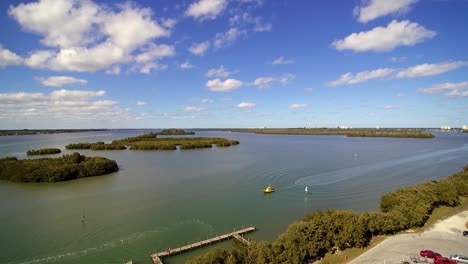 Airal-view-of-the-North-Causeway-off-A1A-in-Ft-Pierce-Florida,-yellow-sea-tow-boat-moving-south-on-the-waterway-at-a-slow-rate-of-speed
