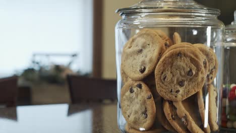 Rack-focus-shot-of-modern-kitchen-across-table-to-jar-of-chocolate-chip-cookies