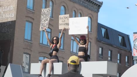 Dos-Mujeres-Negras-Se-Sientan-En-El-Cartel-De-Ottawa,-Protestando-Contra-La-Brutalidad-Policial