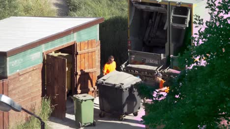 Mann-Leert-Mülltonnen-In-Einen-Müllwagen
