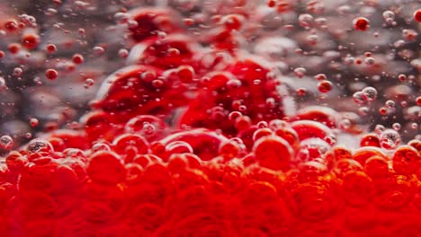 macro-shot-of-red-bubbles-getting-mixed-in-water,-floating-around