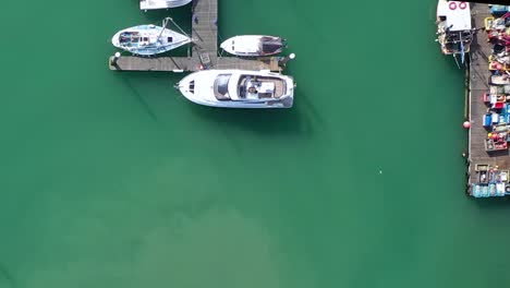 Top-down-aerial-view-of-sailing-boats-and-yachts-moored-on-the-turquoise-waters-of-Brighton-Marina,-UK
