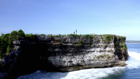People-fishing-on-the-ocean-cliffside-at-New-Kuta-Golf-Course-with-expansive-resort-grounds,-Aerial-approach-shot