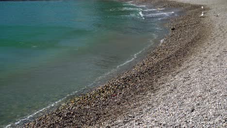 Closeup-of-gentle-waves-lapping-onto-a-tranquil-pebble-beach-in-Collioure-on-a-windy-day