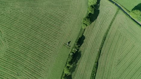 Top-down-aerial-of-a-tractor-turning-over-the-cut-grass-to-make-hay