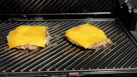 two-homemade-cheeseburgers-cooking-on-a-black-grill
