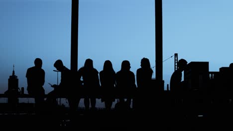 Silhouettes---Group-of-people-is-sitting-together-at-evening-light---slow-motion