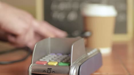 Hands-using-cell-phone-in-cafe-with-payment-terminal-machine-close-up