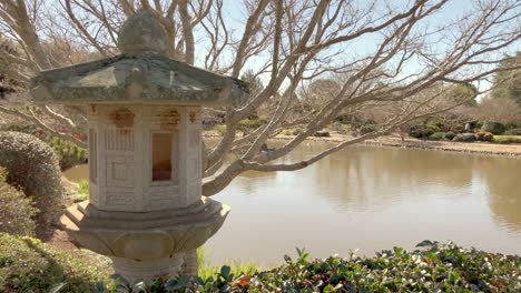 Japanische-Laterne-Mit-Teich-Im-Hintergrund,-Ju-Raku-En-Japanischer-Garten,-Toowoomba,-Australien