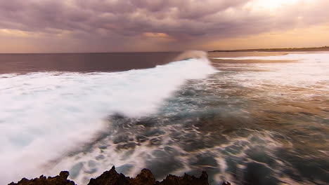 TimeLapse---Waves-rolling-in-during-sunset-with-motion-blur,-moody-clouds-in-sky