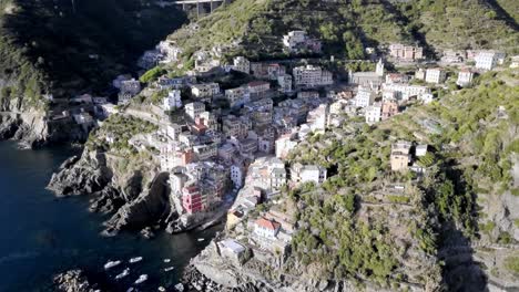 The-Italian-town-of-Riomaggiore-in-the-Cinque-Terre-coastline-with-buildings-built-on-cliffside,-Aerial-drone-dolly-left-reveal-shot