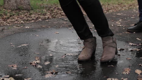 Young-woman's-feet-splash-across-puddle-toward-camera,-slow-motion,-close-up